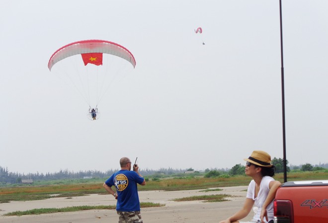 Phiêu bồng với dù bay Phi công Nguyễn Tuấn Võ đang bay với lá cờ Tổ quốc. Dưới đất, anh Julien đang hướng dẫn phi công thông qua bộ đàm
