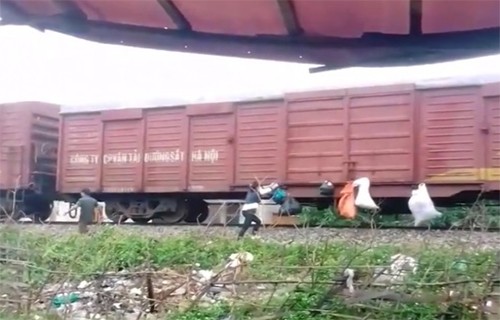 Người 'gửi rác' theo đoàn tàu chạy qua nhà bị phạt ba triệu đồng Cảnh hai người dân đang treo rác lên tàu hàng. Ảnh: Cắt từ video