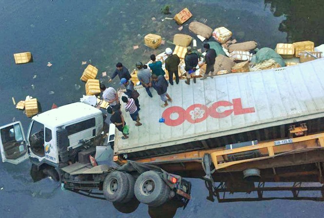 Container tông văng lan can cầu lao xuống sông, một người chết Ngay khi tai nạn xảy ra, hàng chục người dân tham gia trục vớt số hàng hóa bị bung ra khỏi thùng xe.