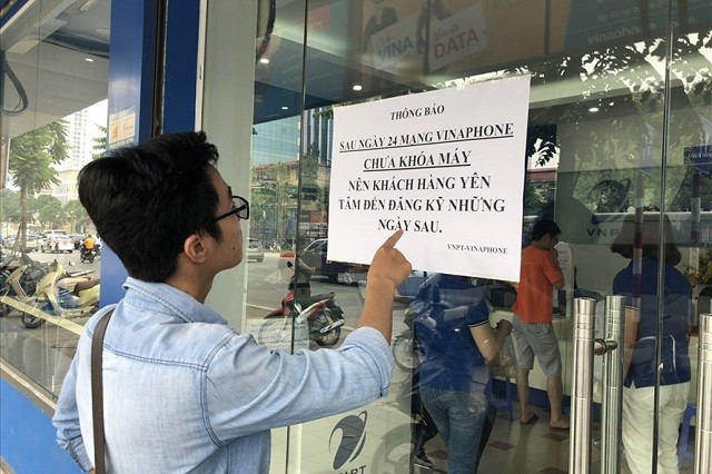 Nhà mạng vẫn quá tải Khách hàng xem thông báo tại một điểm giao dịch của nhà mạng VinaPhone. Ảnh: Việt Dũng.