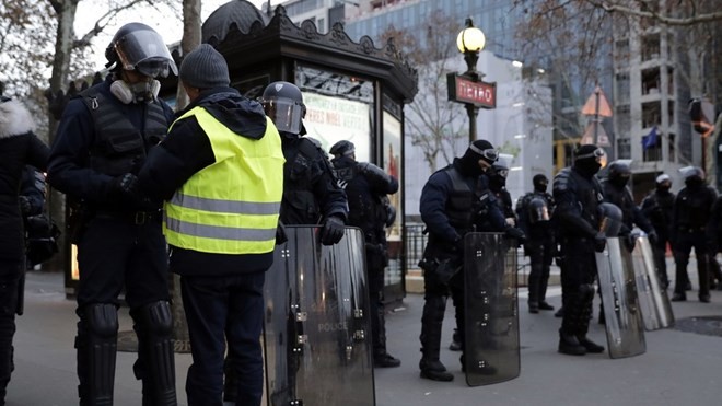 Người biểu tình Pháp bắt đầu tuần hành trên Đại lộ Champs-Elysees Một người biểu tình Áo vàng đứng trước chốt chặn của cảnh sát, ngày 8/12. (Ảnh: AFP)
