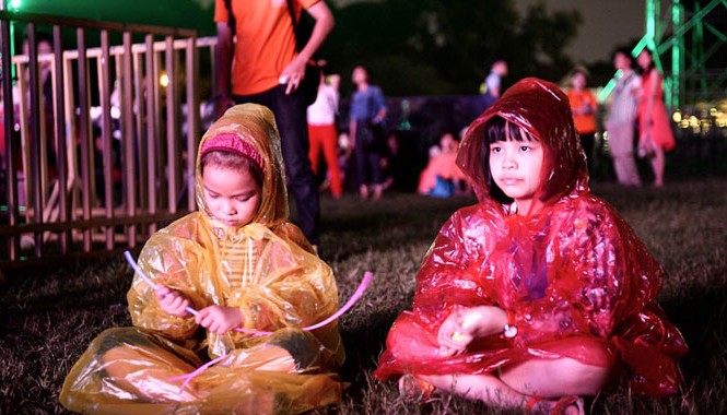 Tôi thấy Gió mùa trong Hoàng Thành Không ít em nhỏ đội mưa đến với Gió mùa, thay vì xem ca nhạc thì lại ngồi chơi thảm cỏ. Ảnh: Dân Trí.