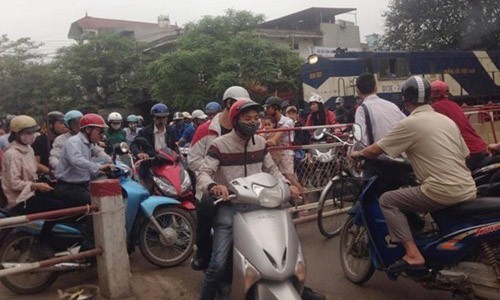 Dân mình có thể làm gì? Đoàn tàu chở hàng buộc phải dừng khi hàng chục người điều khiển xe máy vượt rào chắn băng đường ray trên quốc lộ 21B sáng 13/4. Ảnh: Lê Anh Tú.