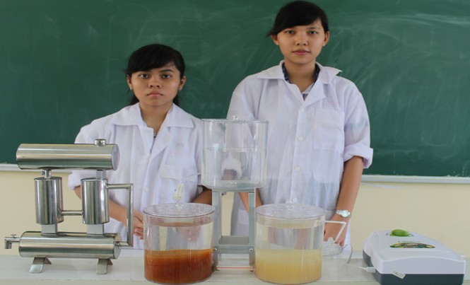 Học sinh trường làng chế “hệ thống xử lý nước mưa khép kín” Thảo Quỳnh (bìa phải) và Hoàng Yến cạnh mô hình “Hệ thống xử lý nước mưa khép kín”. Ảnh: Xuân Lương.