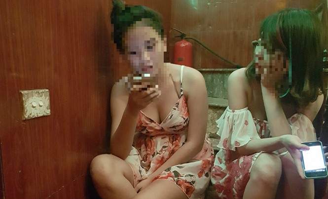 Nghề 'tay vịn' ở quán karaoke Hai cô gái làm PR cho một quán hát ở quận Thanh Xuân, Hà Nội ngồi chờ khách.