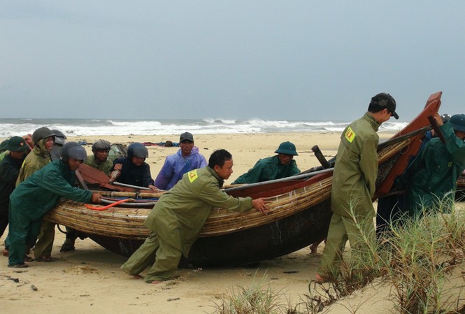 Căng mình chống siêu bão Lực lượng vũ trang Quảng Trị hỗ trợ ngư dân đưa thuyền vào bờ. Ảnh: Thanh Thủy/TTXVN.