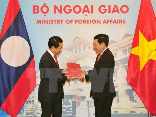 Việt - Lào bàn biện pháp thắt chặt quan hệ song phương Phó Thủ tướng, Bộ trưởng Ngoại giao Phạm Bình Minh và Bộ trưởng Ngoại giao Lào Saleumxay Kommasith trao đổi tượng trưng hai ấn phẩm văn kiên pháp lý biên giới Việt Nam-Lào. (Ảnh: Nguyễn Khang/TTXVN)