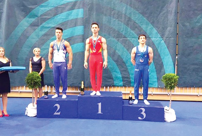 TDDC Việt Nam chạy đà cho ASIAD 2018 Đinh Phương Thành (giữa) trên bục nhận HCV xà kép. Ảnh: HLV Trương Minh Sang.