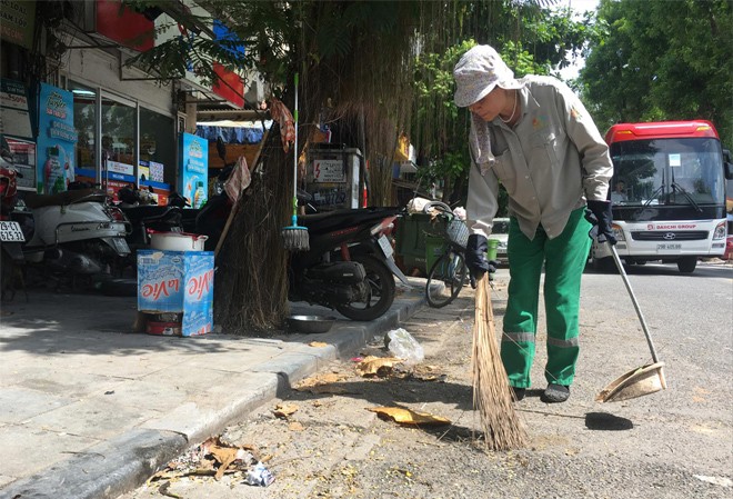 Vì sao quy định về xử phạt xả rác vẫn nằm trên giấy? Công nhân Cty Urenco Hà Nội đi dọn vệ sinh vỉa hè trên phố Phủ Doãn. Ảnh: Trường Phong.