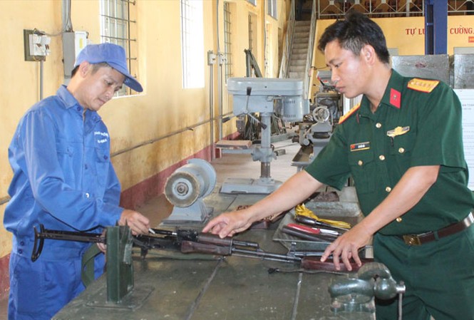Lính thợ tài hoa Thiếu tá Quang (bên trái) đang sửa chữa súng tiểu liên AK tại đơn vị.