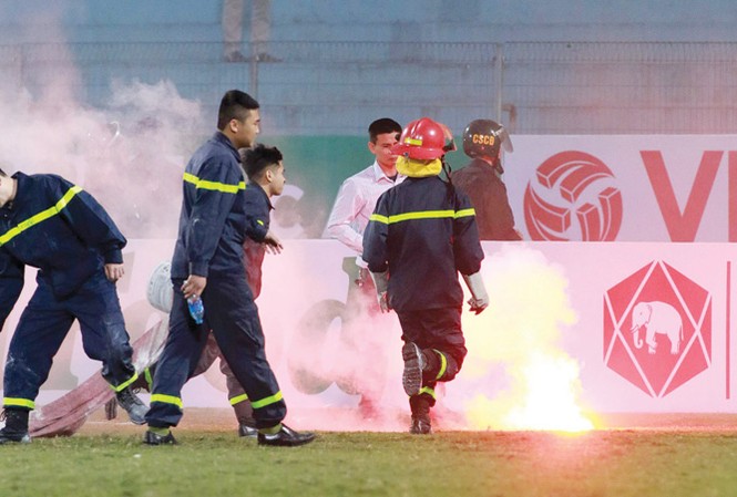 Quyết chặn pháo sáng ở trận cầu đinh vòng 2 V-League Lực lượng cứu hỏa cố gắng dập tắt những quả pháo sáng được CĐV Hải Phòng ném xuống sân Hàng Đẫy ở lượt trận đầu tiên. Ảnh: VSI.