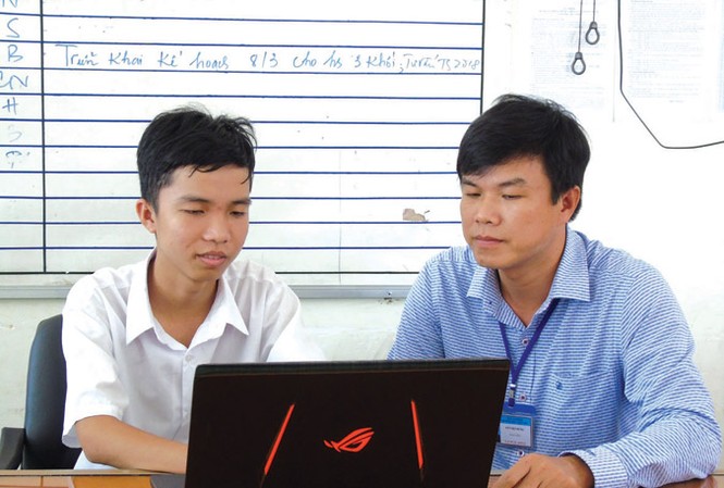 “Ông chủ” nhỏ 10 ứng dụng ở kho Google Play Em Trần Lê Duy (bên trái) và thầy Võ Việt Dũng kiểm tra một số phần mềm đã lập trình. Ảnh: Kim Hà.