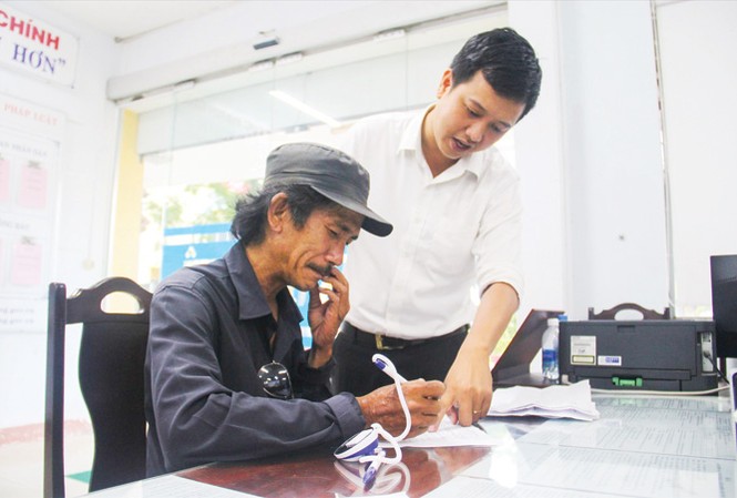 “Biệt đội” gỡ rối thủ tục cho dân Một người dân được các bạn trẻ ở quận Thanh Khê hướng dẫn cách kê khai thông tin vào mẫu đơn. Ảnh: Thanh Trần.