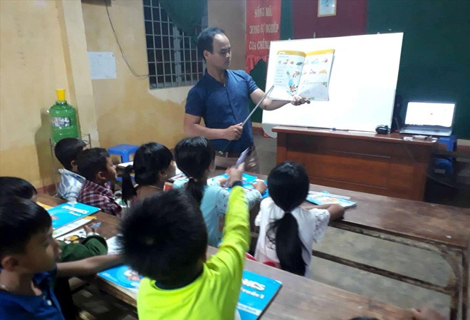 Thầy giáo K’ho dạy tiếng Anh miễn phí cho học sinh nghèo Thầy Lo Minh kèm các em nhỏ học. Ảnh: Nhân vật cung cấp