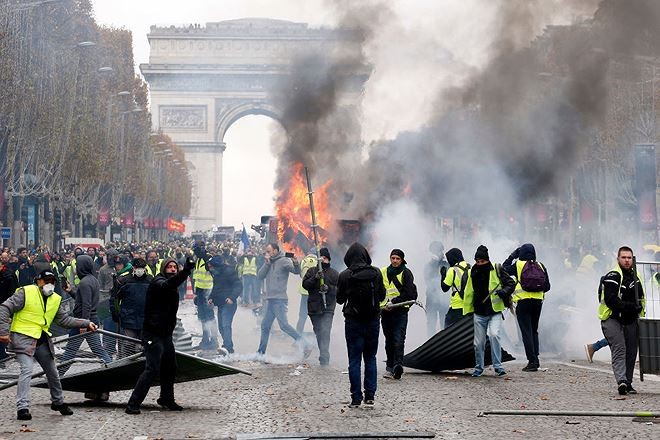 Ðằng sau những đám khói ở Paris Người biểu tình áo vàng trước Khải hoàn môn, Paris. Ảnh: Time