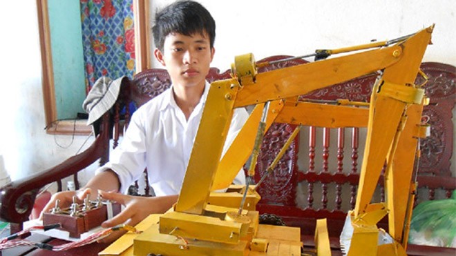 Học sinh lớp 11 chế tạo rô bốt máy cẩu Phát đang vận hành chiếc máy cẩu hai tay múc bán tự động điều khiển từ xa - Ảnh Nhật Linh