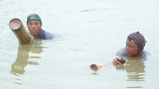 Đời lặn sông Ông Nguyễn Văn Khải (trái) và anh Đại ngoi lên bám vào khúc bương nghỉ lấy sức để rồi lặn tiếp.