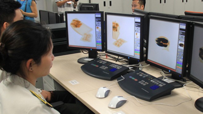Nhân viên vệ sinh sân bay lấy điện thoại của khách Hệ thống kiểm tra an ninh soi chiếu hiện đại tại sân bay Nội Bài. Ảnh: Đ.Loan