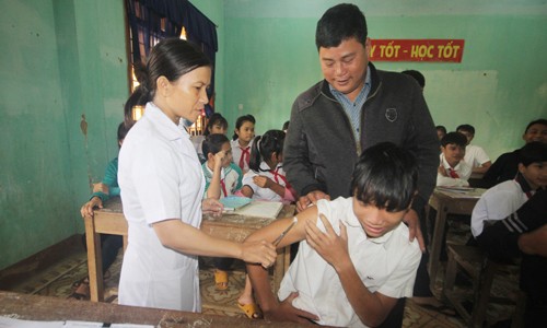 Thầy giáo nhiều sáng kiến hiến đất xây trường Thầy Nguyễn Khắc Điệp động viên học sinh tiêm văcxin bệnh bạch hầu. Ảnh: Đắc Thành.