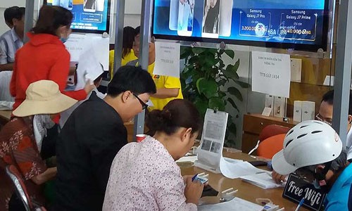 Lỗi nhà mạng, sao chúng tôi phải chịu? Khách hàng đăng ký thông tin cá nhân tại một điểm của nhà mạng MobiFone tại quận 5, TP.HCM. Ảnh: HTD