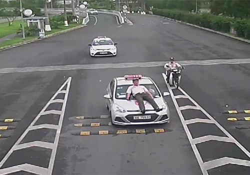Taxi đâm nhân viên an ninh hàng không hoạt động chui ở Hà Nội Tài xế đâm thẳng vào nhân viên an ninh hàng không khiến anh này phải nhảy lên capo. Ảnh cắt từ camera an ninh.