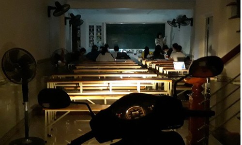 Nhóm học sinh thắp nến, bật đèn pha xe máy ôn thi đại học Lớp học dưới ánh nến và đèn pha xe máy