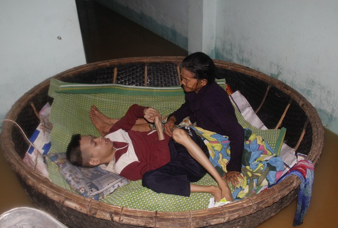 Quặn lòng cảnh mẹ 72 tuổi neo thúng giữ con chất độc da cam giữa lũ Hai mẹ con bà Đắt trong chiếc thuyền thúng nổi trôi theo nước lũ. Ảnh: Thanh Trần.