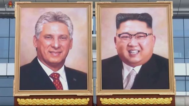 Triều Tiên lần đầu trưng bày tranh chân dung ông Kim Jong-un Tranh chân dung của ông Kim Jong-un được treo cạnh tranh chân dung Chủ tịch Cuba Miguel Diaz-Canel. Bức tranh vẽ ông Kim cười tươi trong bộ vest mang phong cách phương Tây. Ảnh: KCTV