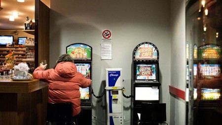 Lombardy: 'Thủ đô cờ bạc' của Italia Một người đang mê mẩn bên máy đánh bạc trong quán bar.