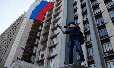 Donetsk của Ukraine đòi sáp nhập vào Nga Một người biểu tình cầm cờ Nga tại trụ sở chính quyền ở Donetsk. Ảnh: Getty.