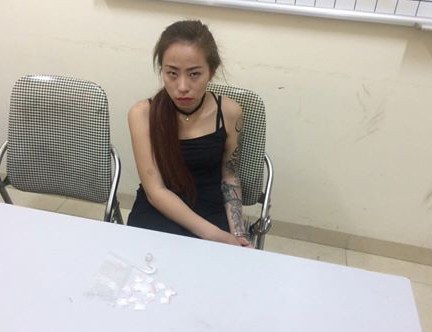 Cô gái xăm trổ giấu 12 gói bột trong áo ngực nghi ma túy Phạm Thùy L và tang vật tại cơ quan công an. Ảnh: Quân Nguyễn.