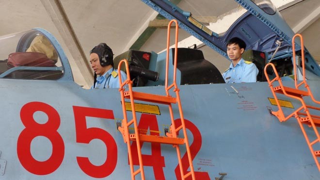 Lính thợ bạc tỷ ở Trung đoàn không quân 935 Thiếu tá Nguyễn Công Tênh (ngồi trước) và trung úy Trần Gia Chuân kiểm tra thiết bị trên máy bay Su 30MK2. Ảnh: T.Đ