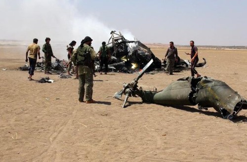 Nhóm người Syria yêu cầu đổi tù nhân lấy thi thể tổ bay Nga Các phiến quân Syria đứng trước xác chiếc trực thăng Nga bị bắn rơi ở tỉnh Idlib hôm 1/8. Ảnh: AFP.