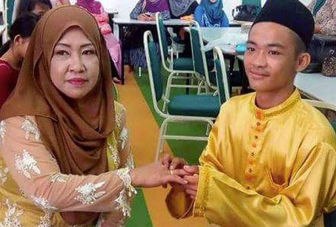 Xôn xao đám cưới giữa trai tân 18 tuổi và 'bà mẹ 5 con' Chú rể 18 tuổi đeo nhẫn cưới vào tay cô dâu 42 tuổi trong đám cưới. Ảnh: Facebook.