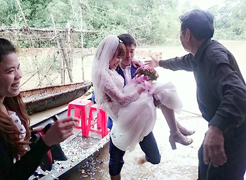 Chú rể đi thuyền, lội nước bế cô dâu Bước xuống thuyền, chú rể xắn quần bế cô dâu qua đoạn nước ngập vào tổ chức lễ cưới trong sự cổ vũ của mọi người. Ảnh: Đ.H.