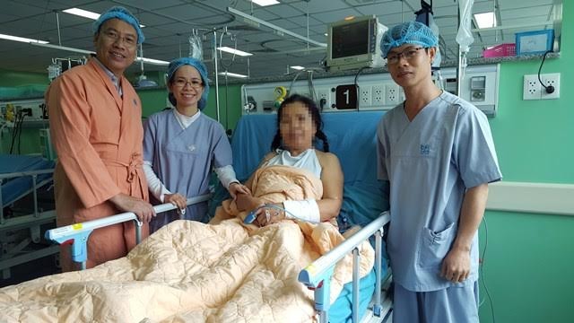 Lạ kỳ người phụ nữ sống với mảnh mìn trong tim suốt 45 năm Bác sĩ Định (áo cam) cùng ê kíp phẫu thuật tim nội soi thăm hỏi bệnh nhân sau ca mổ. Ảnh do bệnh viện cung cấp.