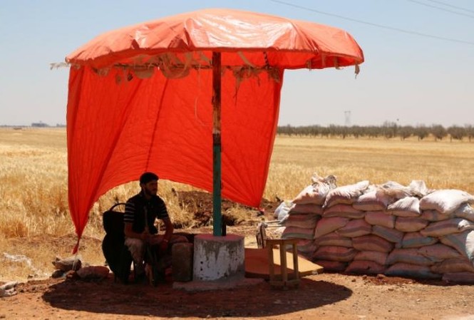 Quân đội Syria tuyên bố ngừng bắn, LHQ lập kế hoạch đàm phán hòa bình Một tay súng của nhóm Quân đội Syria Tự do ngồi nghỉ dưới bóng râm ở làng al-Nuaimah, thành phố Derra ngày 17/6. Ảnh: Reuters