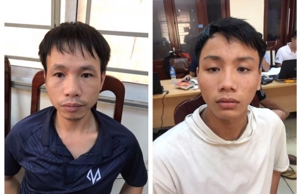 Nghi can đốt pháo dù trúng chân nữ CĐV trên sân Hàng Đẫy khai gì? Vũ Trung Trực (áo tối màu) và Trần Đắc Chương (áo trắng) đang bị tạm giữ để điều tra, xử lý.