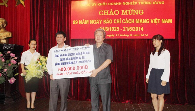 Ủng hộ 500 triệu đồng cho PV làm nhiệm vụ ở Hoàng Sa - Trường Sa Ông Trần Bá Huấn (áo trắng) trao tặng món quà của VDB. Ông Hà Minh Huệ thay mặt cho các PV tiếp nhận. Ảnh: Trần Việt Hải