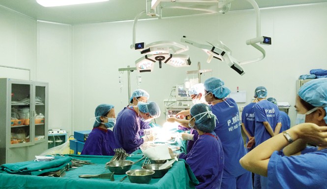 'Chụp cắt lớp' bàn tay vàng ngoại khoa GS.TS Trịnh Hồng Sơn và kíp mổ đang phẫu thuật cho bệnh nhân ung thư. Ảnh: T.Hà.