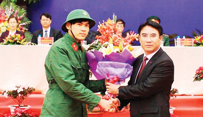 Hoãn du học Anh quốc lên đường nhập ngũ Tân binh Ngô Quang Huy nhận hoa của Chủ tịch UBND Quận Thanh Xuân Nguyễn Xuân Lưu tại lễ giao, nhận quân. Ảnh: Hồng Thái.