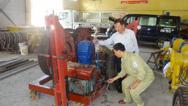 Người đội trưởng nhiều đam mê sáng chế Anh Nguyễn Viết Thắng - Bí thư Chi bộ, Đội trưởng Đội Vận tải cơ khí Công ty Truyền tải điện 1 (áo trắng) cùng đồng nghiệp nghiên cứu thử nghiệm Hợp bộ máy hãm dây 4 tấn.