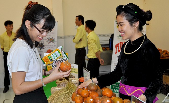 Cô gái Tày đem cam đi “đánh” xứ người Cẩm Ly (phải) đang giới thiệu sản phẩm cam Hàm Yên (Tuyên Quang) cho khách hàng tại Hội chợ hàng Việt Nam chất lượng cao, tháng 3, tại An Giang.