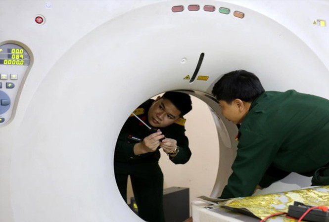 Chuyên gia hồi sinh máy móc Thượng úy Nguyễn Xuân Thành (bên trái) sửa chữa máy chụp CT scanner 1. Ảnh: NVCC.