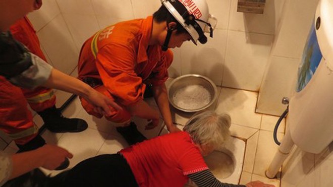Kẹt tay 4 tiếng trong bồn cầu vì lấy răng giả bị rơi Các nhân viên cứu hộ đang nỗ lực giải thoát cho bà Trương.