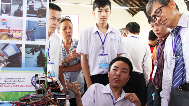 Nam sinh bại liệt chế robot giúp người khuyết tật Trần Phan Thanh Hải đang giới thiệu mô hình robot hỗ trợ người bị bại liệt. Ảnh: Mạnh Tùng
