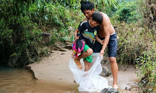 Học sinh chui túi nilon qua suối ở Điện Biên: Chủ tịch huyện tiếc nuối Học sinh Na Sang phải chui qua túi nilon nhờ người lớn đưa qua suối. Ảnh: VOV.