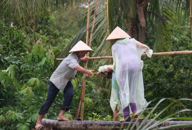 ‘Xây cầu đến lớp’ – cần nhiều hơn nữa những tấm lòng Chú Khá hỗ trợ người dân đi qua cầu tạm Út Ốm trong những ngày mưa