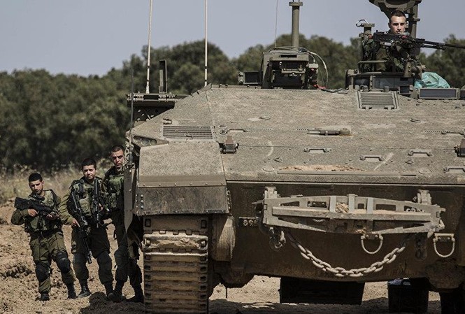 Quân đội Israel bất ngờ tập trận quy mô lớn Lính Israel đứng cạnh một chiếc xa tăng gần biên giới Israel Gaza. Ảnh: AP