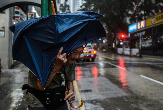 Macao lần đầu tiên đóng cửa sòng bài vì siêu bão Mangkhut Một cụ bà che ô đứng đợi taxi tại Hồng Kông sáng 16/9. Ảnh: Getty